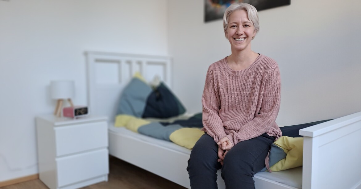 Eine Frau sitzt auf einem Bett