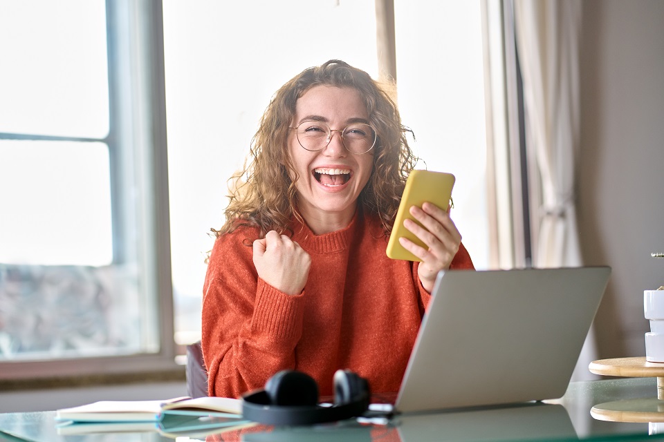 Young happy lucky woman student feeling excited winner holding cellphone using mobile phone winning online, receiving great news or sms offer on smartphone, getting new job celebrating success. © insta_photos Young,Happy,Lucky,Woman,Student,Feeling,Excited,Winner,Holding,Cellphone